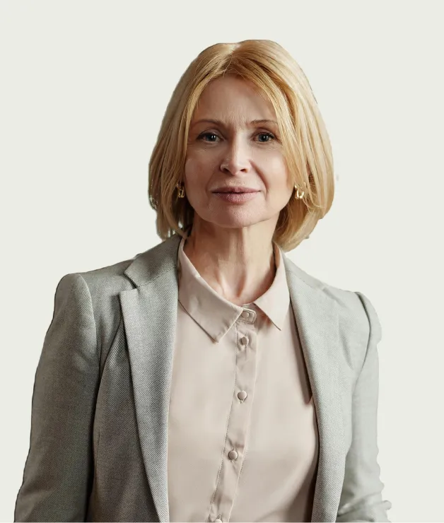 Professional woman in a light blouse and gray blazer, posed for a corporate headshot against a pale background.